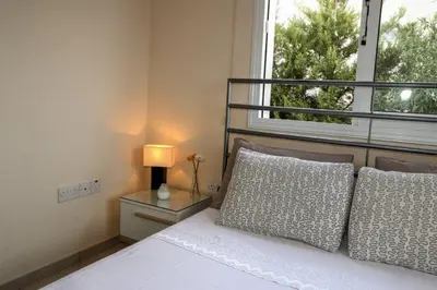 a bedroom with a bed with a lamp and a window at Villa Anastasia in Ayia Napa