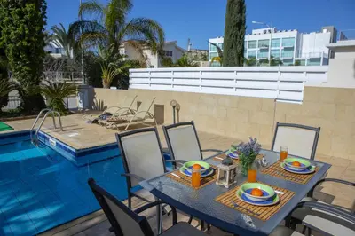 a table and chairs next to a swimming pool at Protaras Villa Marilia in Protaras