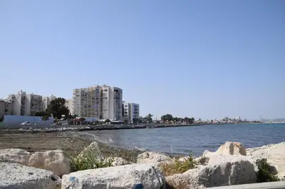 a beach with rocks and buildings in the background at Sea Krystel 603 in Larnaka