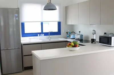 a white kitchen with a bowl of fruit on a counter at Villa St. Nicolas 8 - Protaras in Protaras