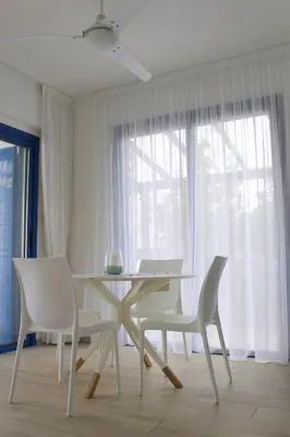 a white dining room with a table and two chairs at Villa St. Nicolas 8 - Protaras in Protaras