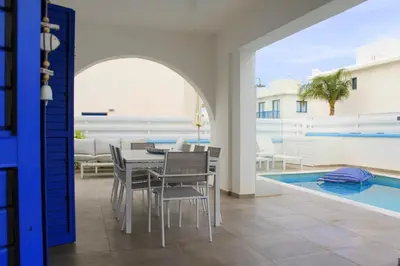 a dining room with a table and chairs next to a swimming pool at Villa St. Nicolas 8 - Protaras in Protaras