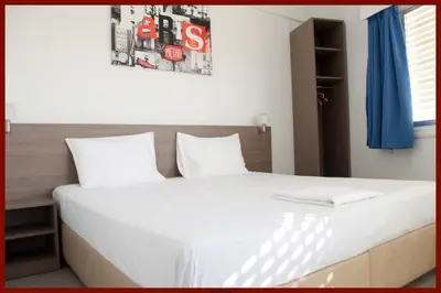 a bedroom with a large bed with white sheets at St. George Rent Rooms in Larnaka