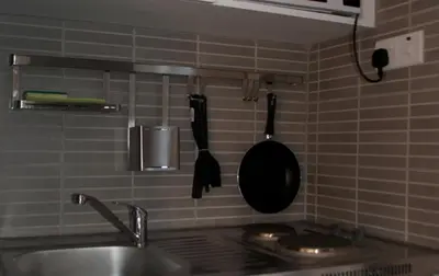 a kitchen with a sink and a frying pan on the wall at St. George Rent Rooms in Larnaka