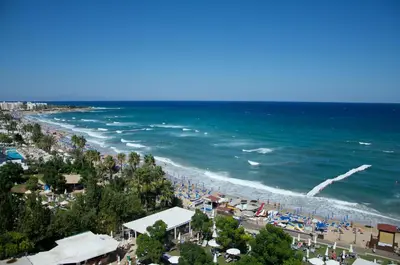 a beach with a crowd of people and the ocean at Spacious 1 Bedroom Apartment in Kapparis Area in Paralimni