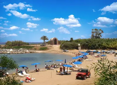 a beach with a bunch of people and blue umbrellas at Spacious 1 Bedroom Apartment in Kapparis Area in Paralimni