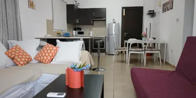 a living room with a couch and a kitchen at Cosy apartment in a luxury resort in Paralimni