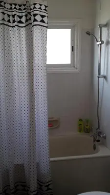 a bathroom with a shower curtain and a tub and a window at LIRA in Larnaka