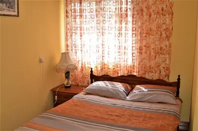 a bedroom with a bed and a window with a lamp at LIRA in Larnaka