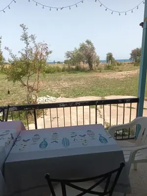 a table and chairs on a porch with a view of a field at Mazotos beach house in Mazotos