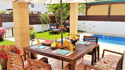 a wooden table with fruit on a patio with a pool at Palm Paradise Villa in Ayia Napa