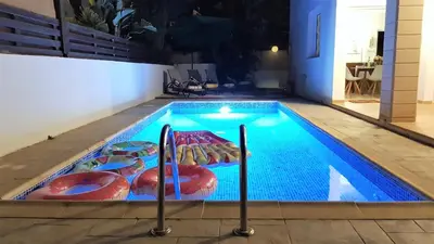 a swimming pool with four chairs in it at Palm Paradise Villa in Ayia Napa