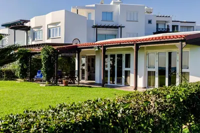 a house with a green lawn in front of it at Blue Bay Beach House in Larnaka