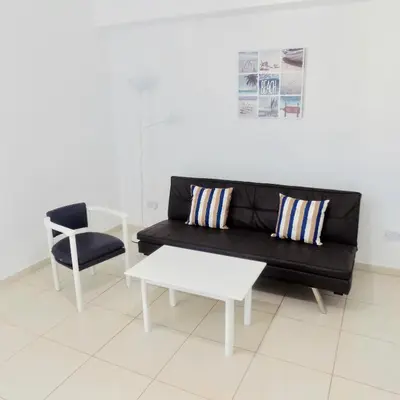 a living room with a black couch and a chair at Margarita Napa Apartments in Ayia Napa