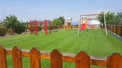 a playground with a large grassy field with a wooden fence at BG04 Mythical Sands in Paralimni