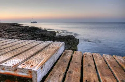 a wooden bench sitting on the edge of the ocean at Villa Elaine in Paralimni