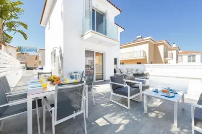 a patio with a table and chairs and a pool at Villa Elaine in Paralimni