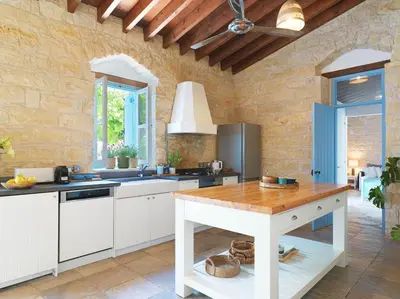 a kitchen with white cabinets and a wooden table at Villa Avgoustis in Pachna