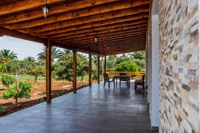 an outdoor patio with a table and a wooden ceiling at BerryRose Villa in Pervolia