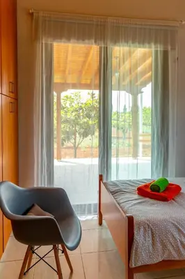 a bedroom with a bed and a chair next to a window at BerryRose Villa in Pervolia