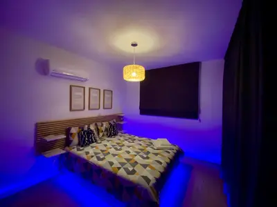 a bedroom with a tv and a bed with blue lights at Fat Cow Apartment 103 in Larnaka
