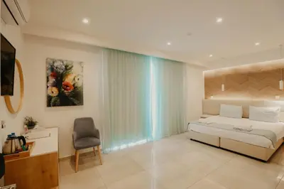 a bedroom with a bed and a chair and a window at Hai Hotel in Larnaka