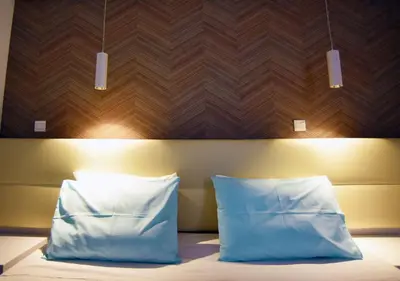a bed with two pillows and a wooden head board at Hai Hotel in Larnaka