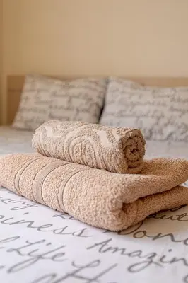 a pile of towels sitting on a bed at Lovely Bedroom in shared apartment Oroklini in Voroklini