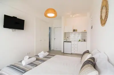 a white living room with a couch and a tv at Larnaka Seaview Luxury Suites in Larnaka