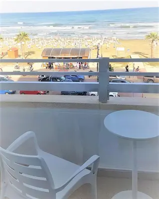 a white chair and a table in front of a beach at Larnaka Seaview Luxury Suites in Larnaka