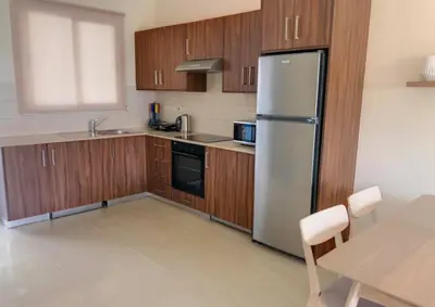 a kitchen with wooden cabinets and a stainless steel refrigerator at Mythical Sands Luxury Apartment in Paralimni