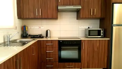a kitchen with wooden cabinets and a stove and microwave at Mythical Sands Luxury Apartment in Paralimni