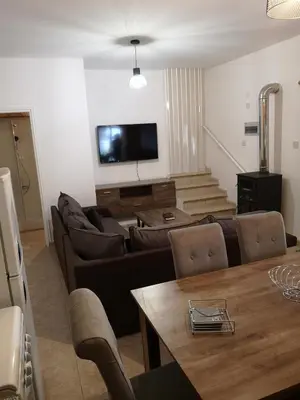 a living room with couches and a table and a tv at Aprosmeno Jacuzzi House 1 in Agros