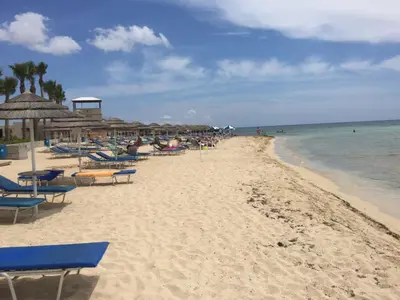 a beach with chairs and umbrellas and the ocean at 2 Bed Flat - Sleeps 4 - Pool - Parking - Wifi in Xylophaghou