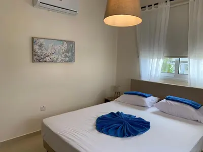 a bedroom with a white bed with blue pillows at Mythical Sands new Luxury Apartment in Paralimni