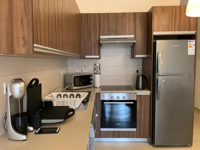 a kitchen with stainless steel appliances and wooden cabinets at Mythical Sands new Luxury Apartment in Paralimni