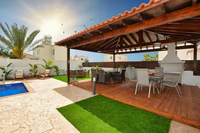 a patio with a table and chairs under a pergola at Villa Nissi Gold in Ayia Napa