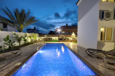 a swimming pool in the backyard of a house at night at Villa Nissi Gold in Ayia Napa