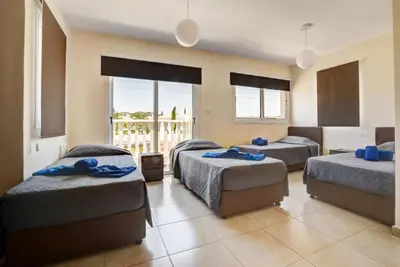 a bedroom with three beds and a balcony at Villa Nissi Gold in Ayia Napa