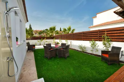 a patio with a table and chairs on the grass at Nissi Palms Villa in Ayia Napa