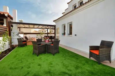 a patio with chairs and a table on grass at Nissi Palms Villa in Ayia Napa