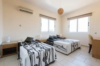 two beds in a room with two windows at Nissi Palms Villa in Ayia Napa