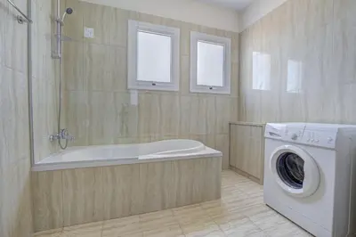 a bathroom with a tub and a washing machine at Nissi Palms Villa in Ayia Napa