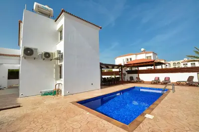 a villa with a swimming pool in front of a building at Nissi Palms Villa in Ayia Napa