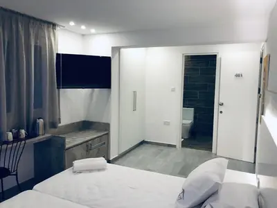 a white bedroom with a bed and a bathroom at White 11 in Larnaka
