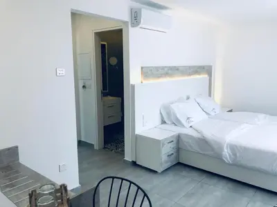 a white bedroom with a bed and a chair at White 11 in Larnaka
