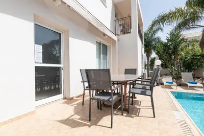 a patio with a table and chairs next to a swimming pool at Konnos Villa Ekaterina in Protaras