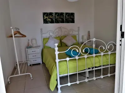 a bedroom with a white bed with a green comforter at Lemon Tree Courtyard in Larnaka