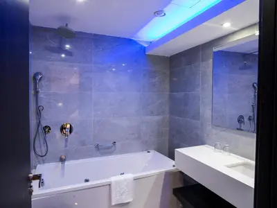 a bathroom with a white tub and a sink at Frangiorgio Hotel in Larnaka