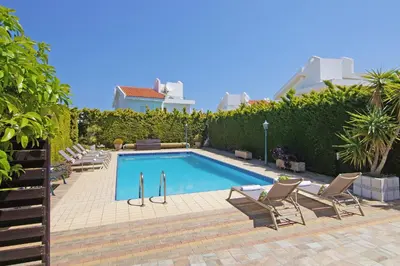 a swimming pool with two chairs next to at Villa Aleta in Protaras